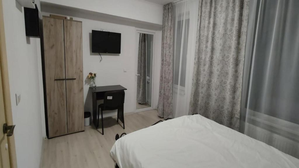 a bedroom with a bed and a desk and a television at Camera de la Bunici - o poarta catre oriunde 