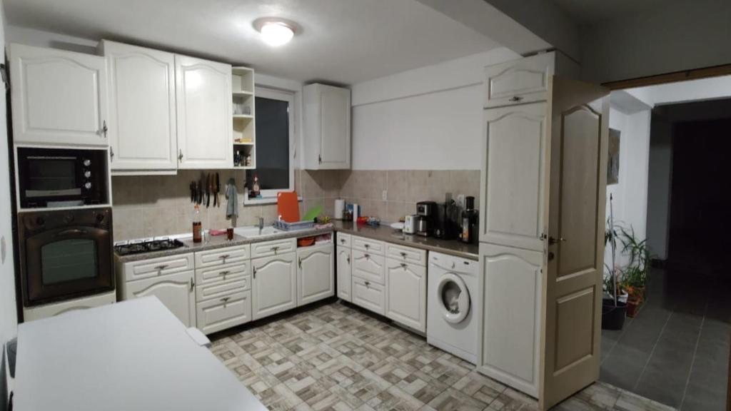 a kitchen with white cabinets and a washer and dryer at Camera de la Bunici - o poarta catre oriunde 