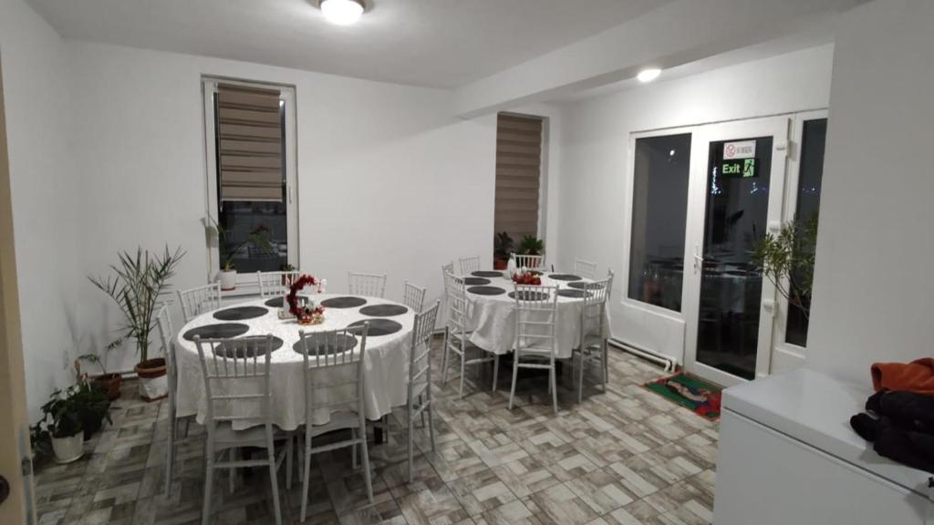 a dining room with white tables and chairs at Camera de la Bunici - o poarta catre oriunde 