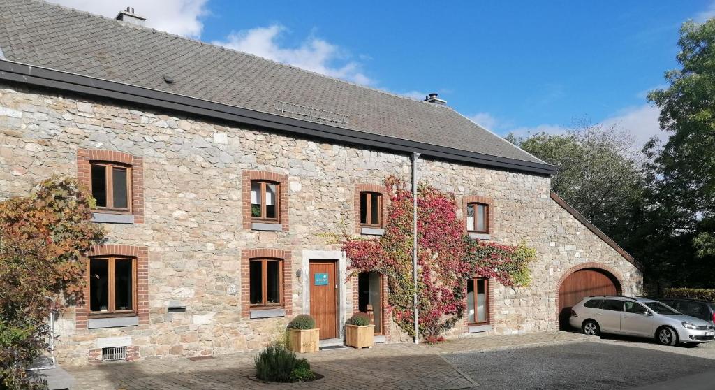 un bâtiment en pierre avec une voiture garée devant. dans l'établissement Une Chambre à Foyr ?, à Jalhay