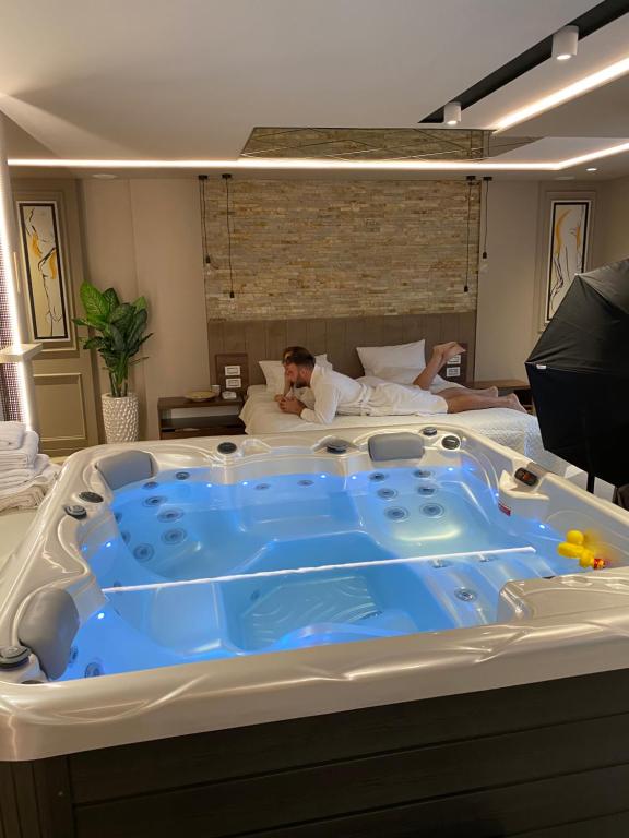 a man laying in a bed with a large tub at Spa Pleasure Apartman in Novi Sad