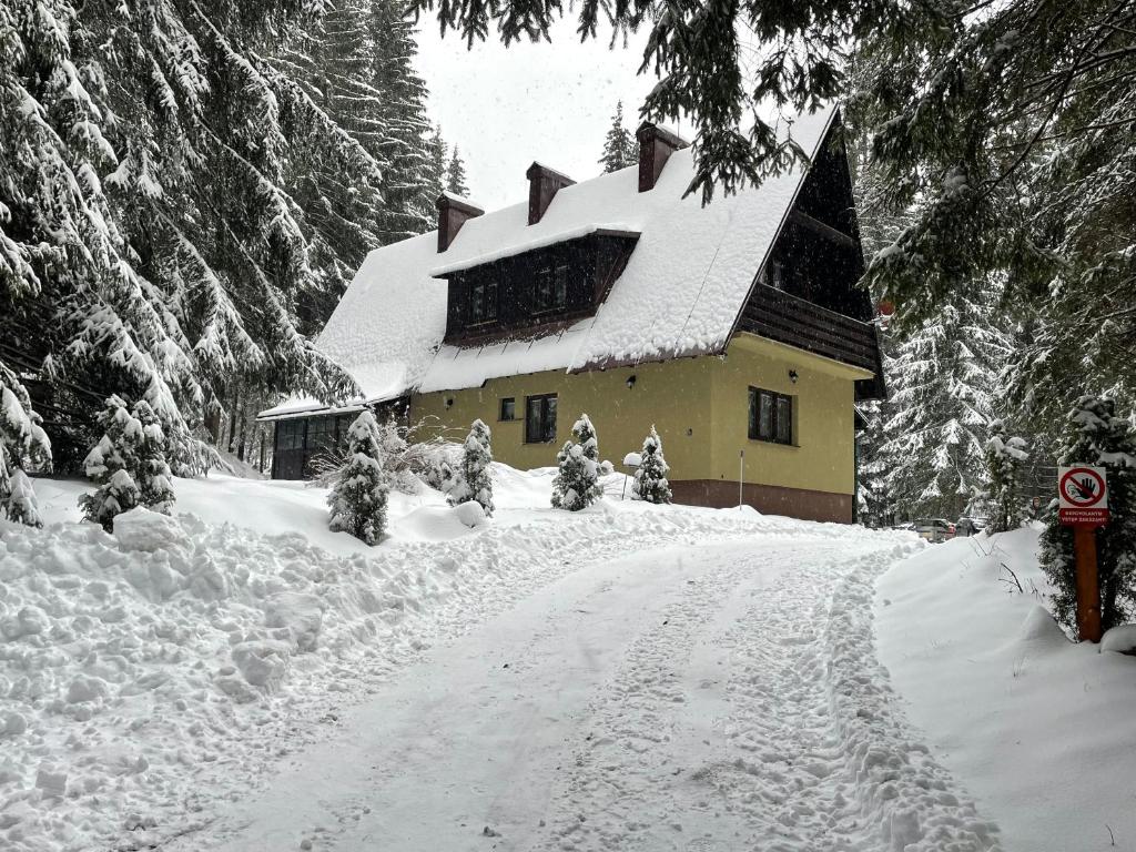 a house covered in snow on a snow covered road at Apartmány Foresta Jasná in Belá