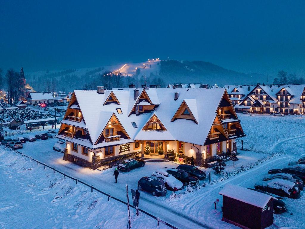 a large house with a snow covered roof in the snow at Dworek Myśliwski Hubert-świetna lokalizacja 50m od Term Bania ,100m od wyciągu Kotelnica in Białka Tatrzańska