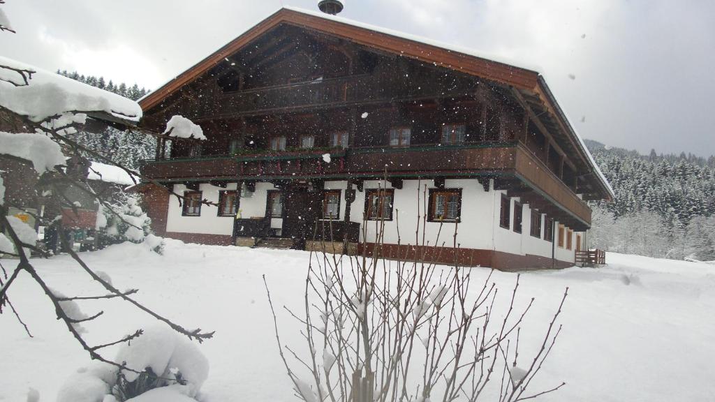 un grande edificio in legno con la neve di Pension Schwaighof a Oberau