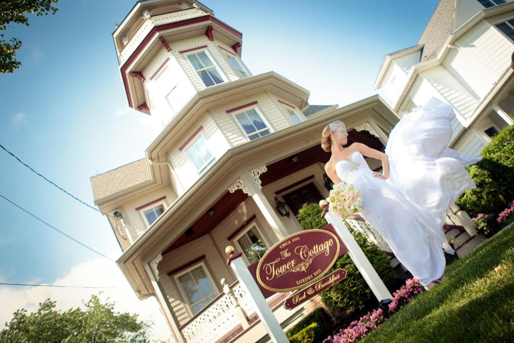 een vrouw in een trouwjurk voor een huis bij The Tower Cottage Bed and Breakfast in Point Pleasant Beach