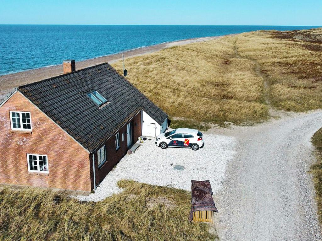 un coche aparcado frente a una casa en un camino de tierra en 10 person holiday home in Fr strup, en Lild Strand