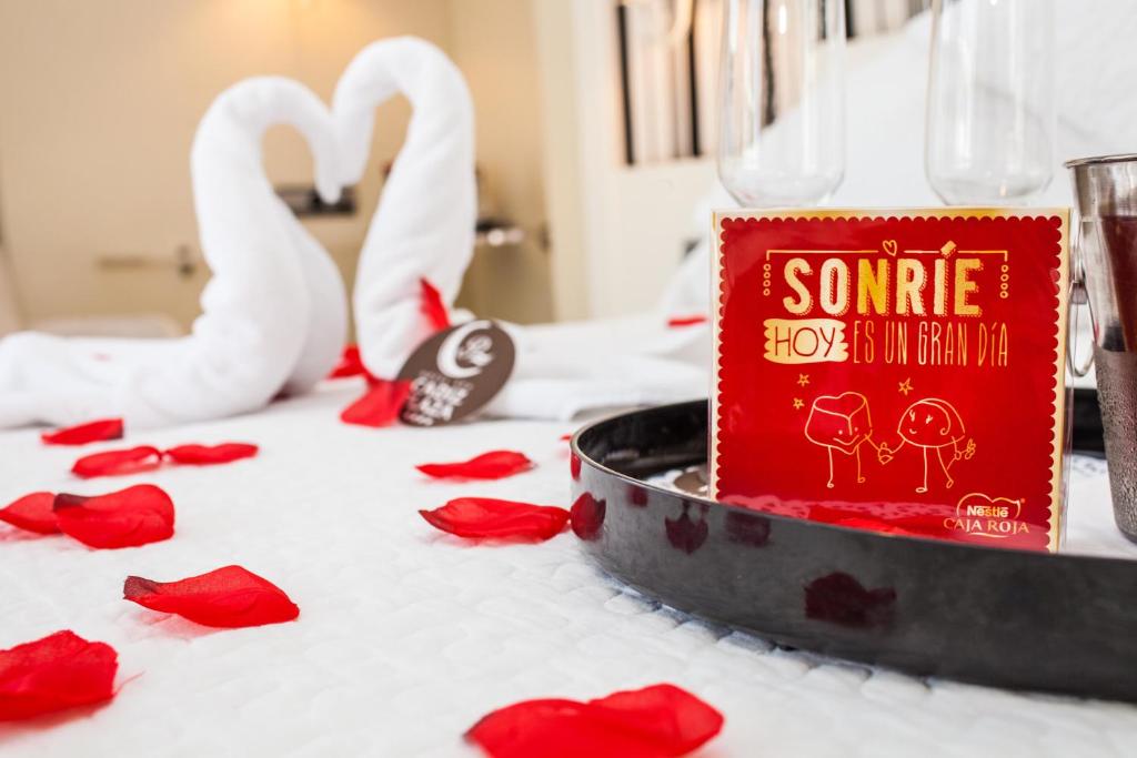 una mesa con rosas rojas y un libro y cisnes en Hotel Spa Cádiz Plaza en Cádiz