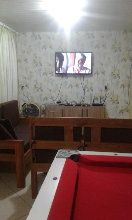 sala de estar con TV de pantalla plana en la pared en casa na praia da pinheira, en Palhoça