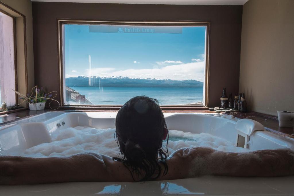 una persona tumbada en una bañera con ventana en Tangoinn Hostel Downtown en San Carlos de Bariloche