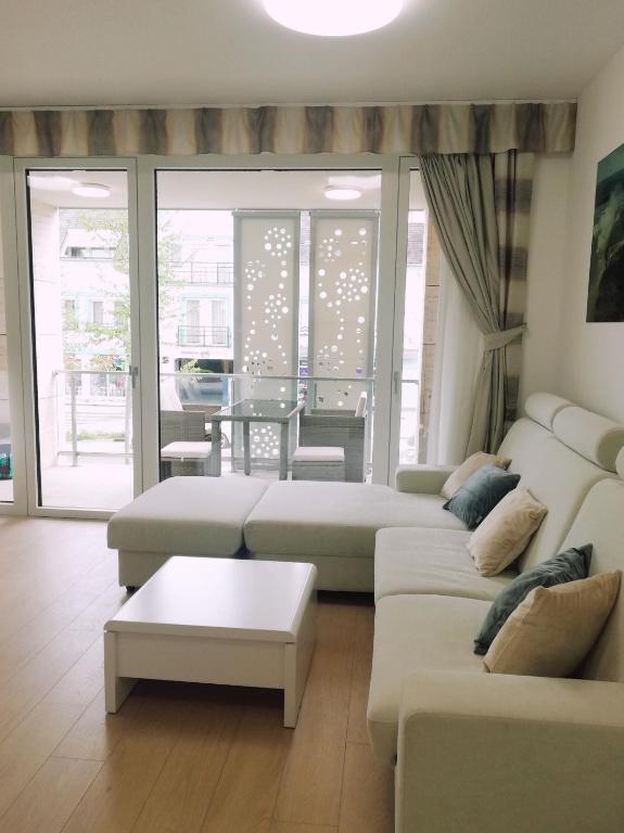 salon z 2 białymi kanapami i stołem w obiekcie Spa Residence Carbona Iguacu Apartman w Hévízie