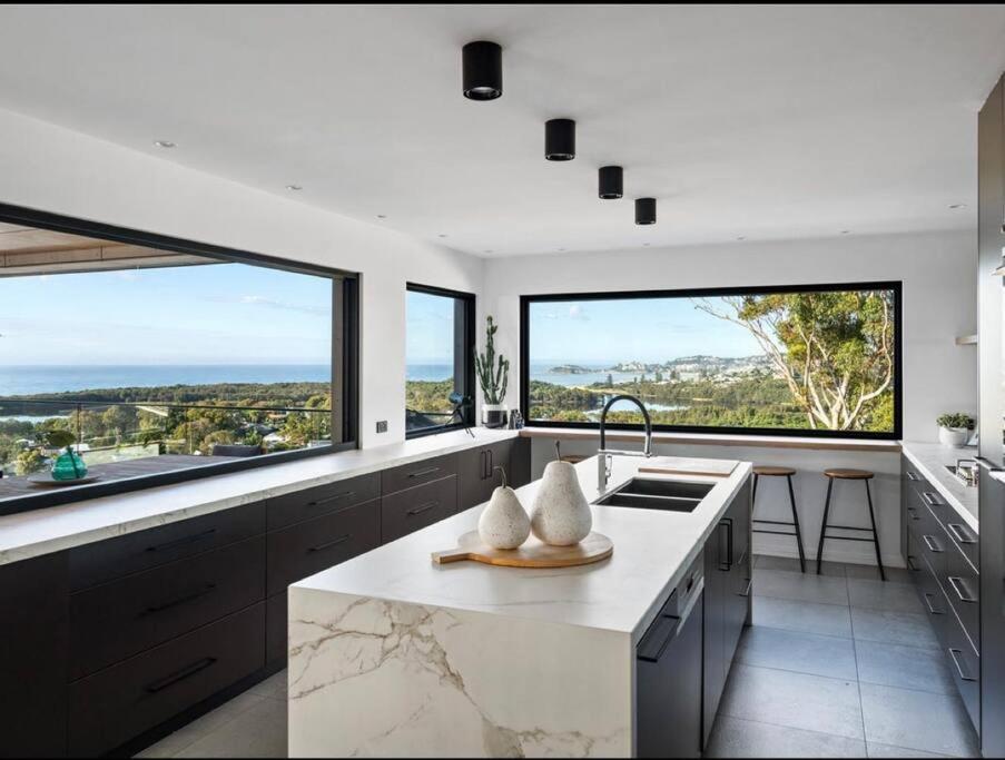 cocina con ventanas grandes y encimera blanca en Luxe Terrigal beach Ocean View with Infinity pool en Wamberal