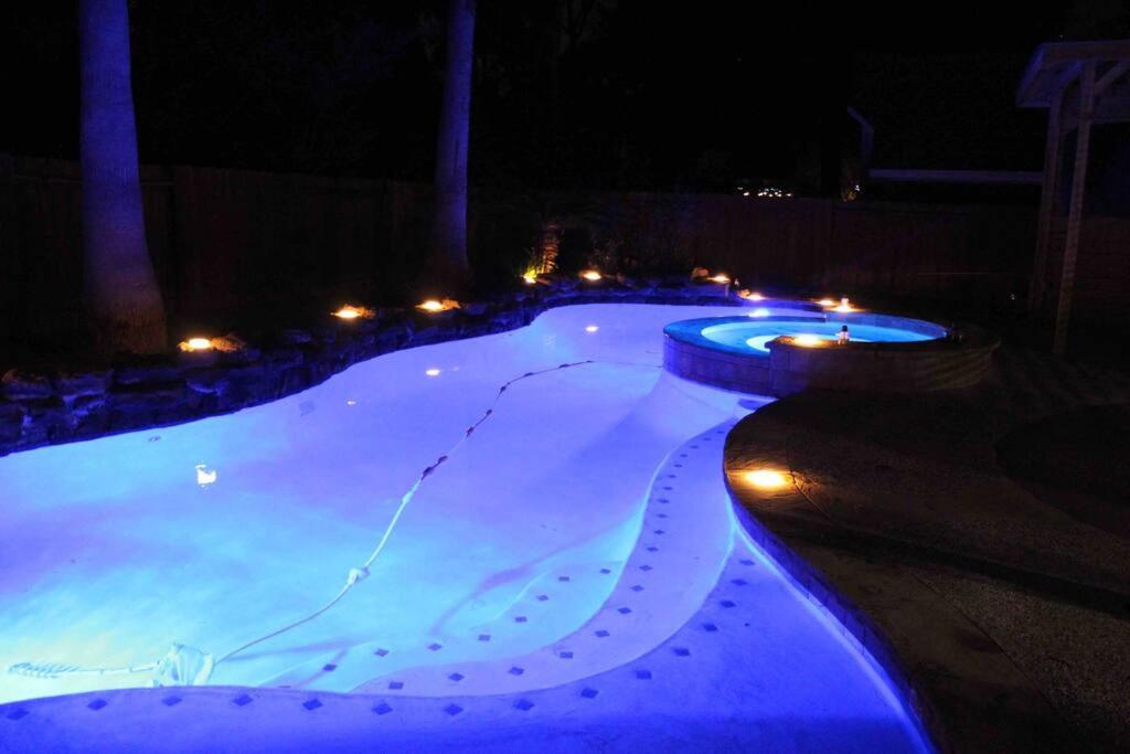 ein Schwimmbad in der Nacht mit Lichtern darin in der Unterkunft ALOHA In The Woodlands! 5BD/3BA Hawaiian Oasis in Conroe