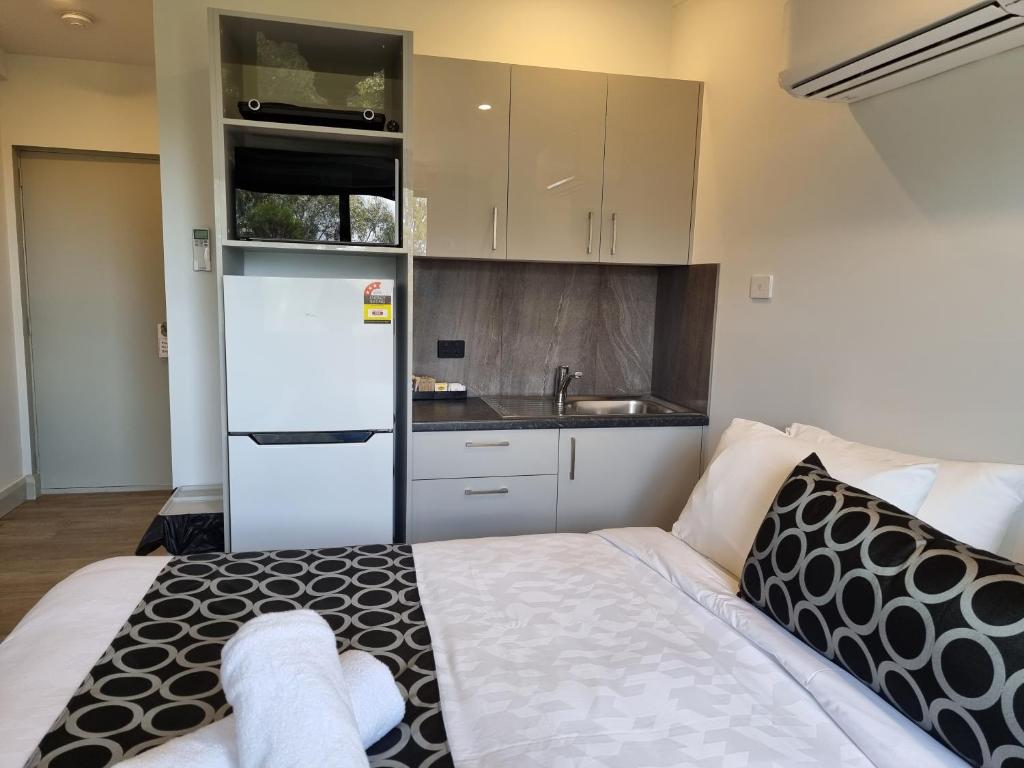 a small bedroom with a bed and a white refrigerator at Cooma High Country Motel in Cooma