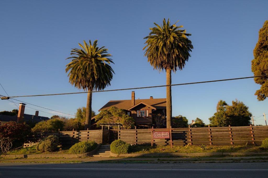 a house with palm trees in front of a fence at The Captains Quarters in Fort Bragg