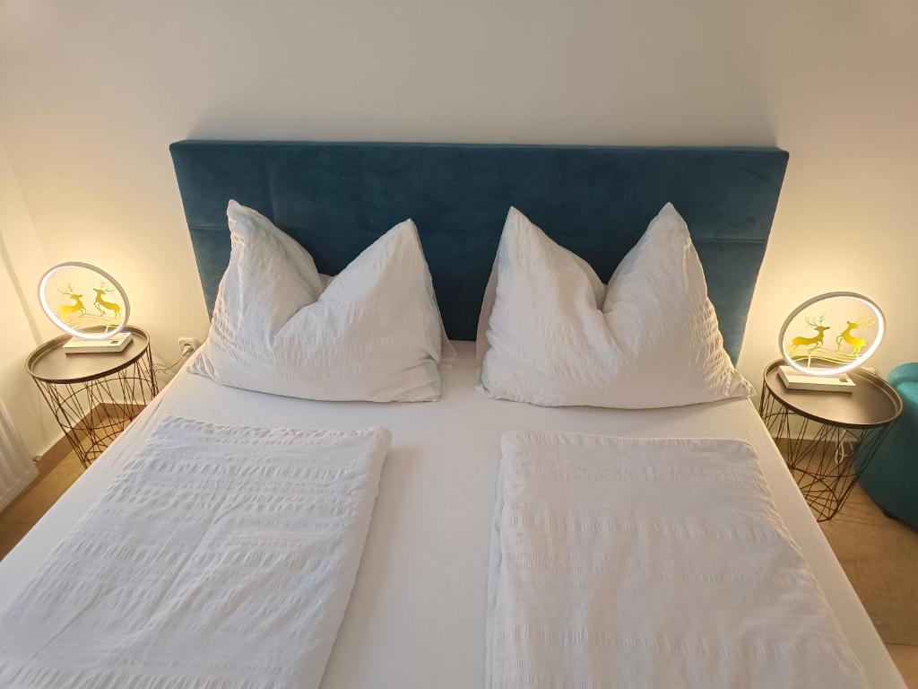 a bed with white pillows on it with two lamps at Ruyi holiday in Sopron