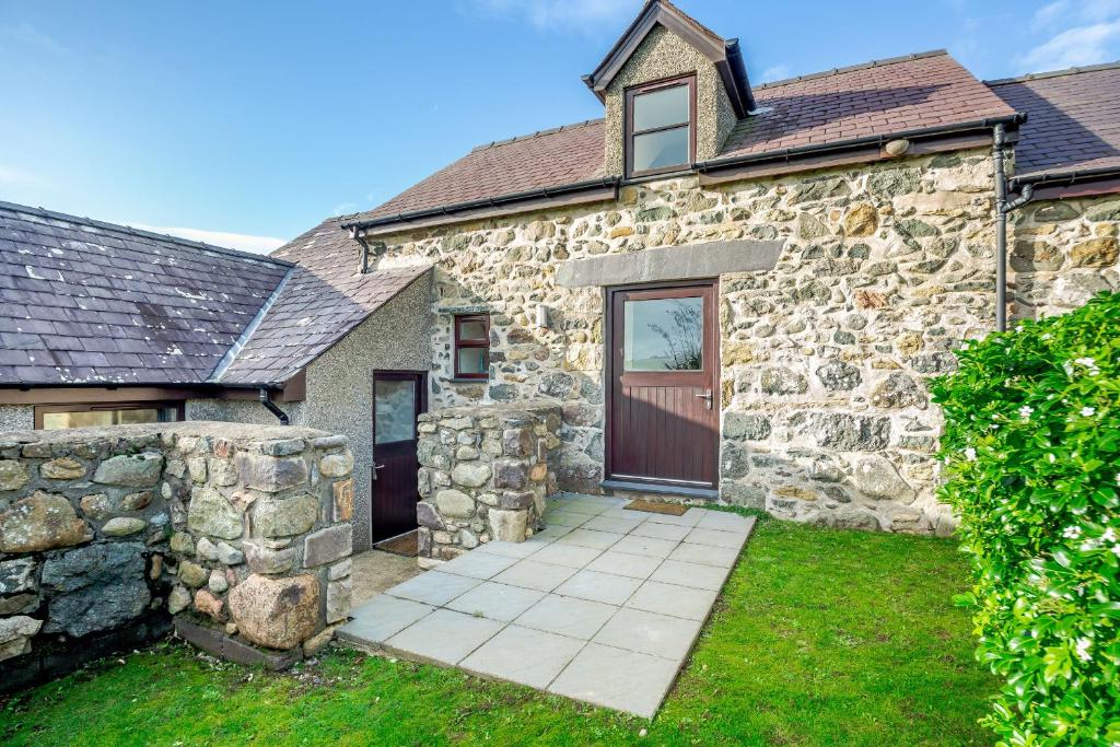 a stone house with a door and a stone wall at Bwythyn-y-Wennol in Abersoch