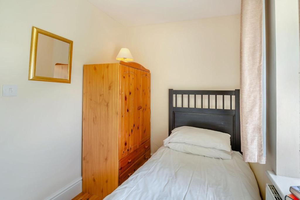 a bedroom with a bed and a wooden cabinet at Bwythyn-y-Wennol in Abersoch