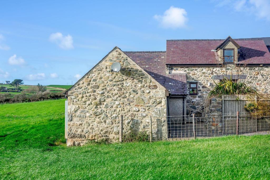 an old stone building in a green field at Bwythyn-y-Wennol in Abersoch