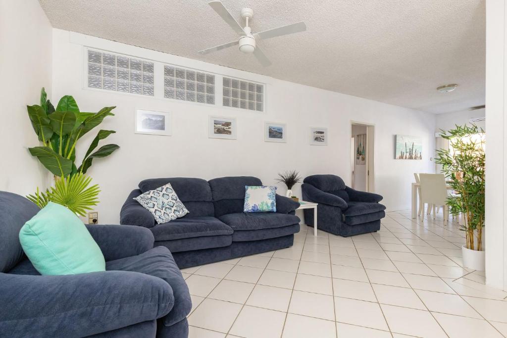 a living room with blue couches and a ceiling fan at Carinya Gardens 15 in Forster