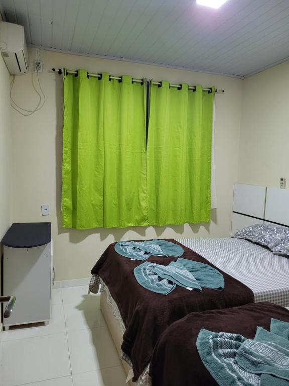 1 dormitorio con 2 camas y cortina verde en Casa para alugar, en Foz do Iguaçu