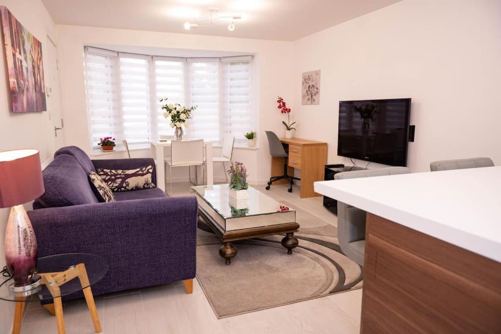 sala de estar con sofá púrpura y TV en Panorama House, Delightful 2-Bedroom Flat 1, Oxford, en Kidlington