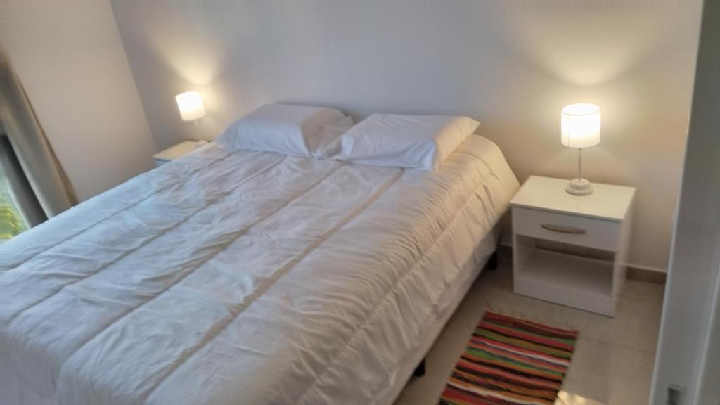 a bedroom with a white bed with two lamps at Bahia sin fondo in Puerto Madryn