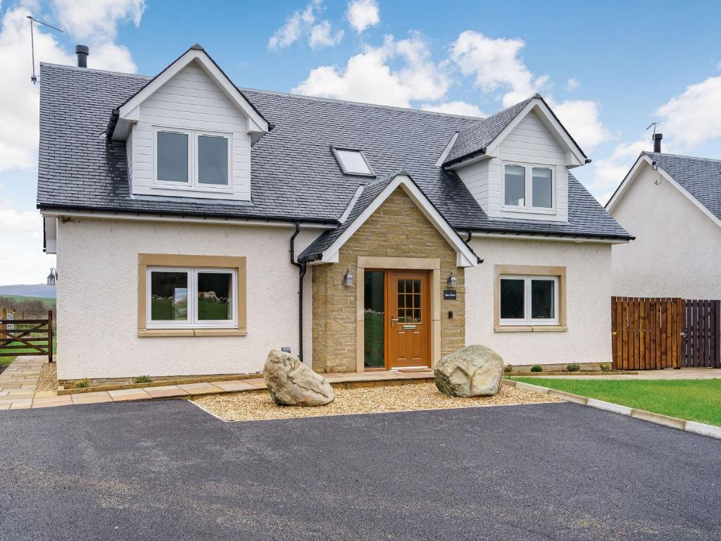 a white house with two large rocks in the driveway at Iora Rua-uk40006 in Gartmore