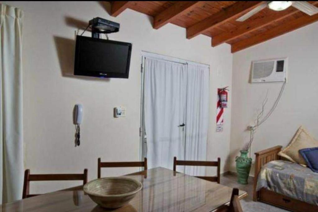 a living room with a table and a tv on the wall at Alojamientos en Cosquín in Cosquín