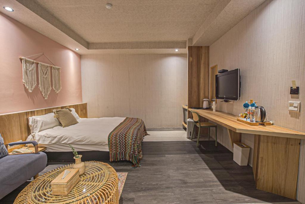 a hotel room with a bed and a desk with a tv at Ashare Hotel in Jiaoxi