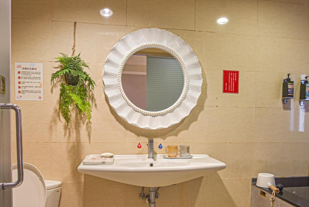 a bathroom with a sink and a mirror on the wall at Ashare Hotel in Jiaoxi
