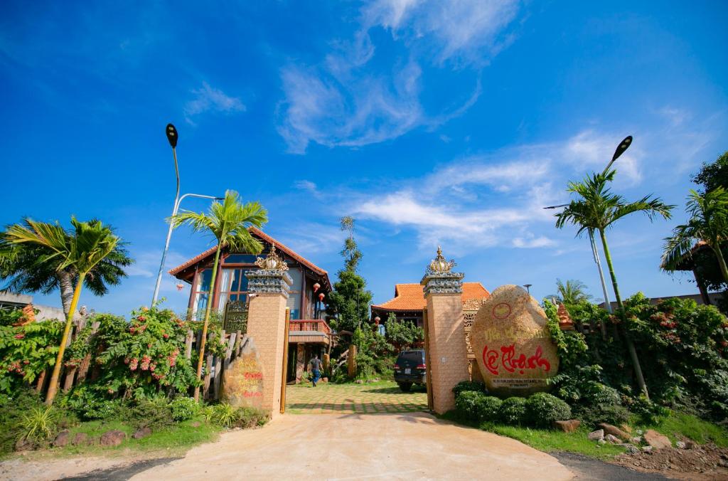 ein Schild vor einem Haus mit Palmen in der Unterkunft HomesStay Lê Thạnh in Hồ Tràm