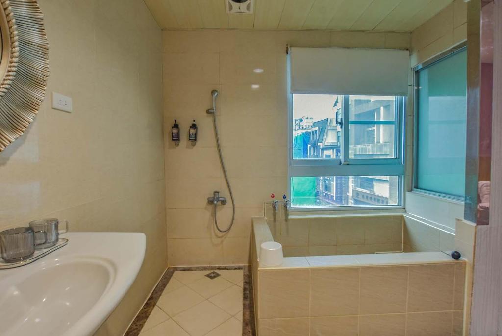 a bathroom with a shower and a tub and a sink at Ashare Hotel in Jiaoxi