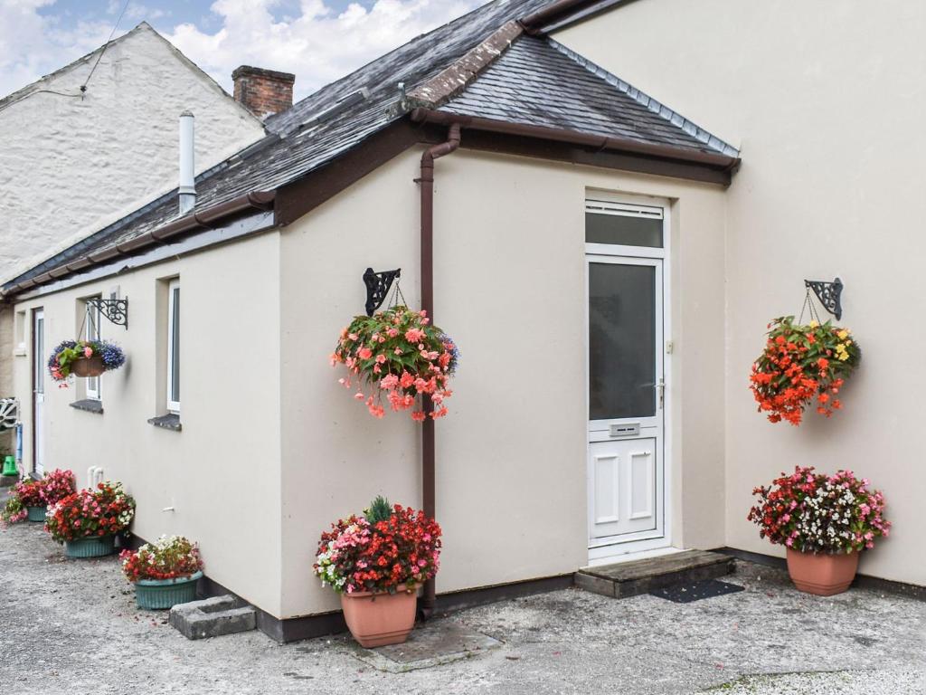 Anneth Lowen في Perranwell: بيت ابيض مع قدور الزهور جانبيه