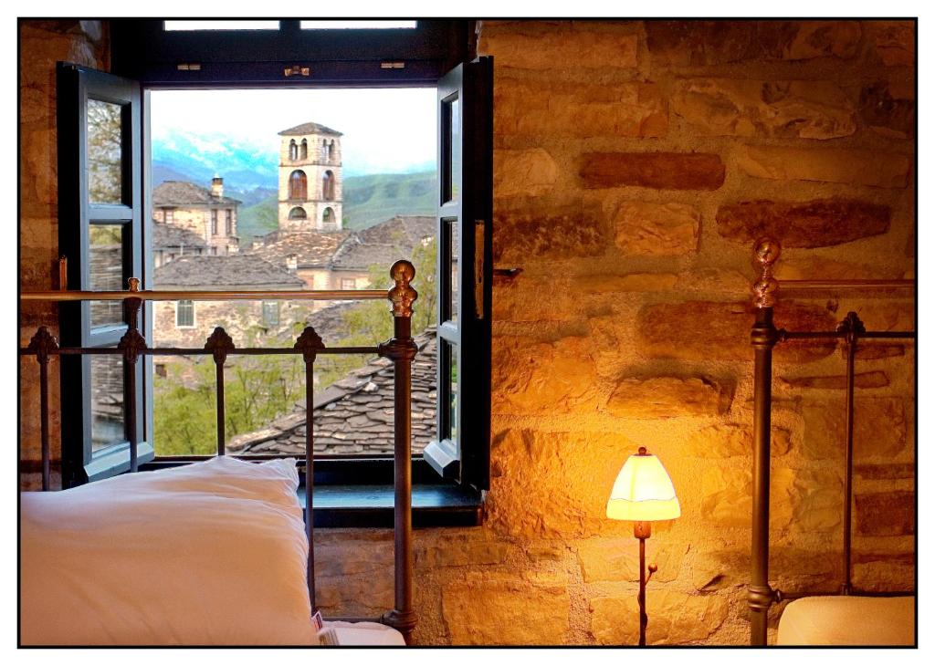 a bedroom with a window with a view of a church at Gaia Guesthouse in Dilofo