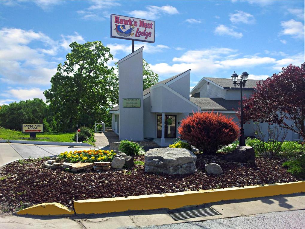 a building with a sign in front of a flower garden at Hawk's Nest Lodge in Osage Beach