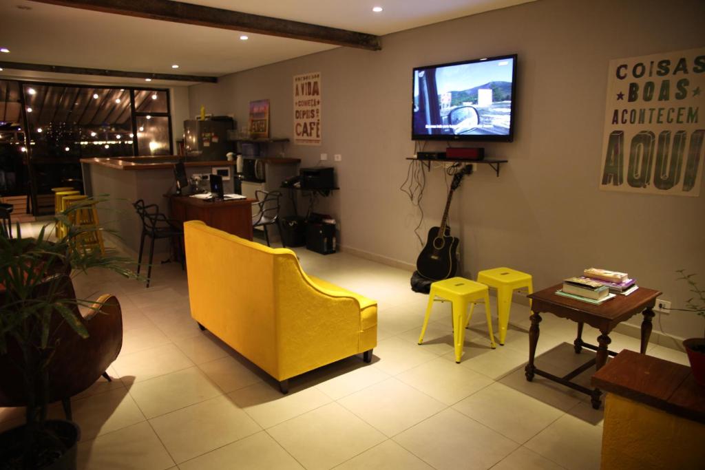 sala de estar con sofá amarillo y TV en Soul Hostel Av Paulista Bela Vista 1 en São Paulo
