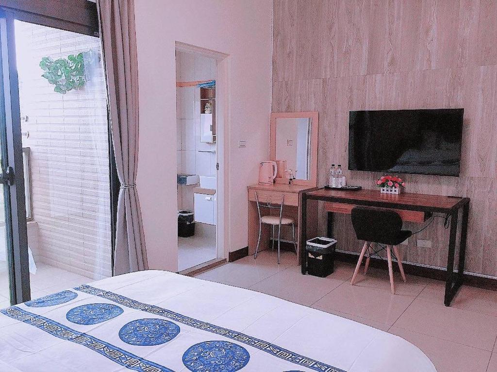 Schlafzimmer mit einem Schreibtisch und einem Tisch mit einem TV in der Unterkunft 親愛的民宿 in Jinning
