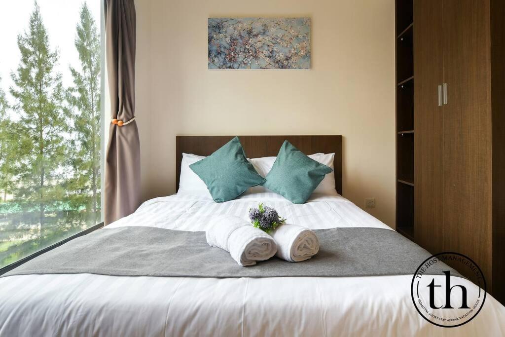 een slaapkamer met een bed met handdoeken en een raam bij Swiss Garden Resort Residences 2BR-5-7 in Kuantan