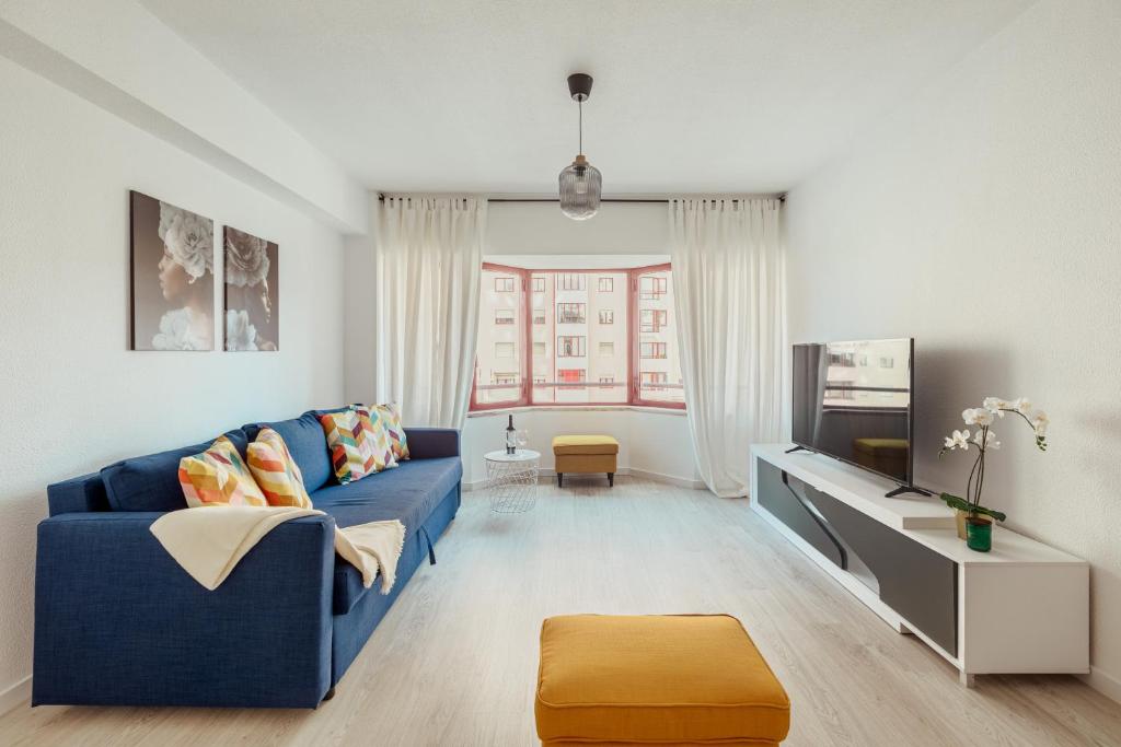 a living room with a blue couch and a tv at Elegant 3 bedroom apt - City centre - garage - metro in Lisbon