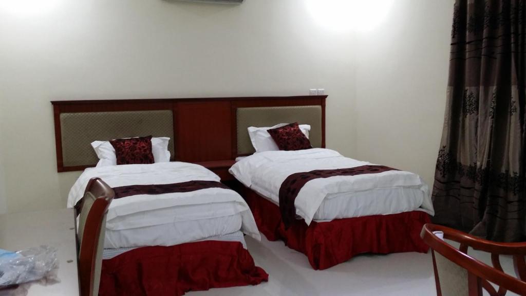 1 dormitorio con 2 camas con sábanas blancas y marrones en Hana Yanbu Hotel Apartments, en Yanbu