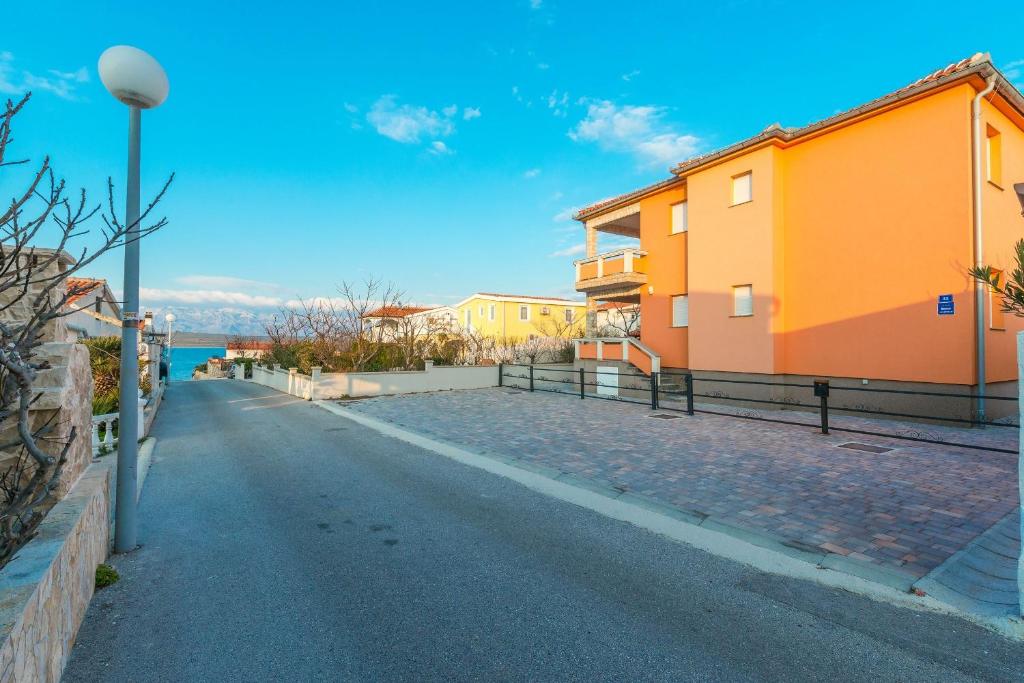Une rue vide avec des bâtiments orange et l'océan dans l'établissement Apartments Kovacevic, à Vir