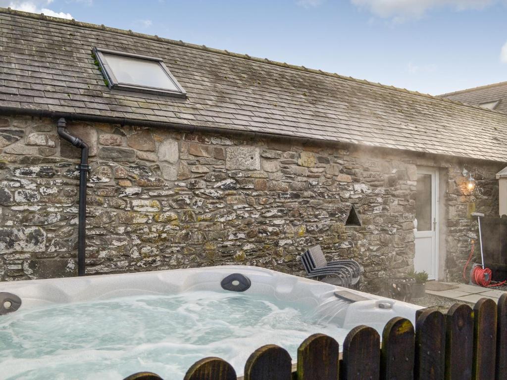 a bath tub in front of a stone building at The Stables - Uk41958 in Laurieston