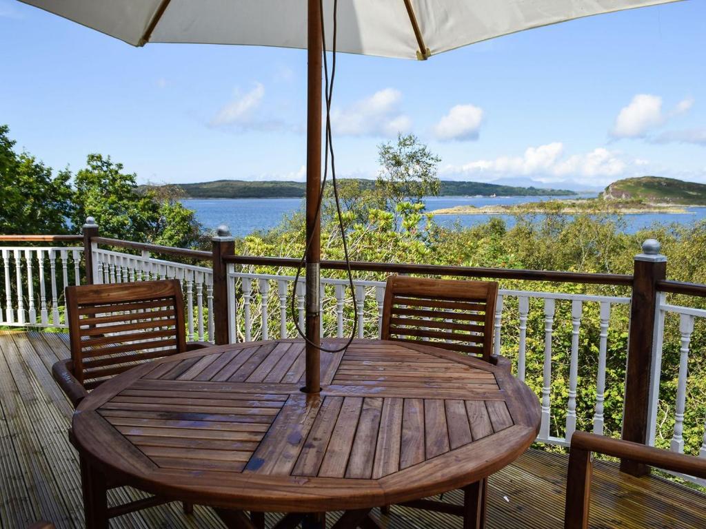 una mesa de madera en una terraza con sombrilla en Teasel Lodge - Uk39647, en Lunga