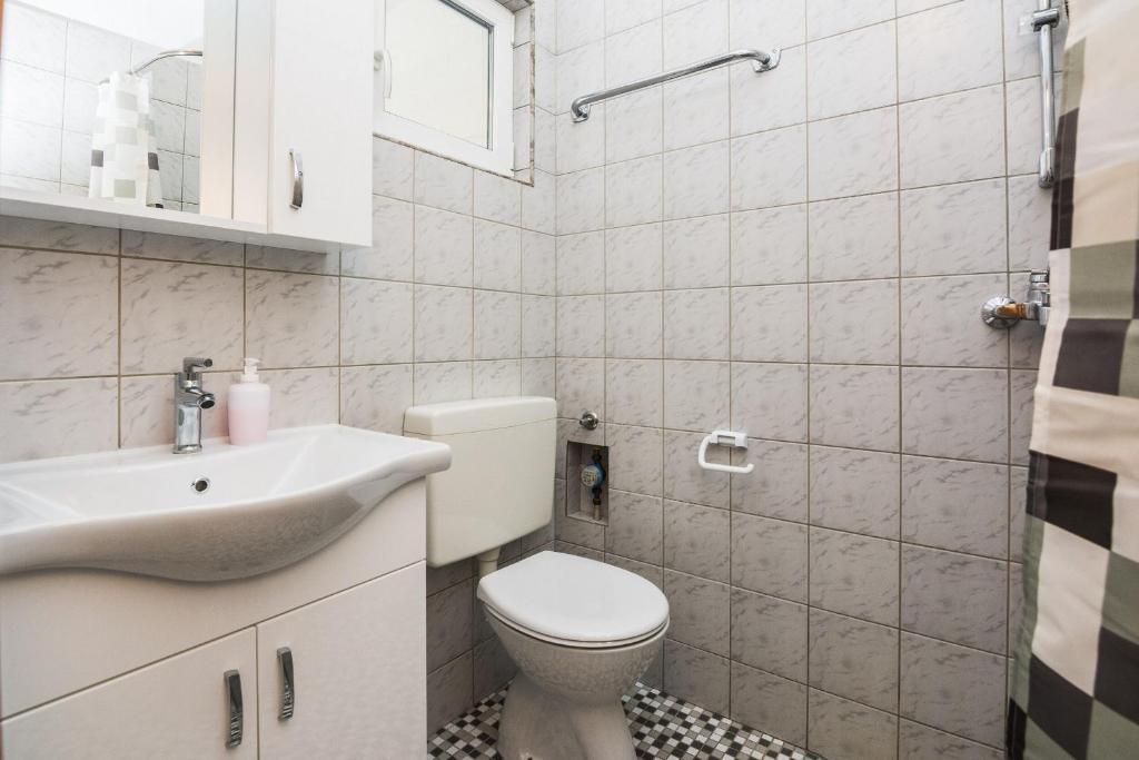 biała łazienka z toaletą i umywalką w obiekcie Apartments Skundric w mieście Vir