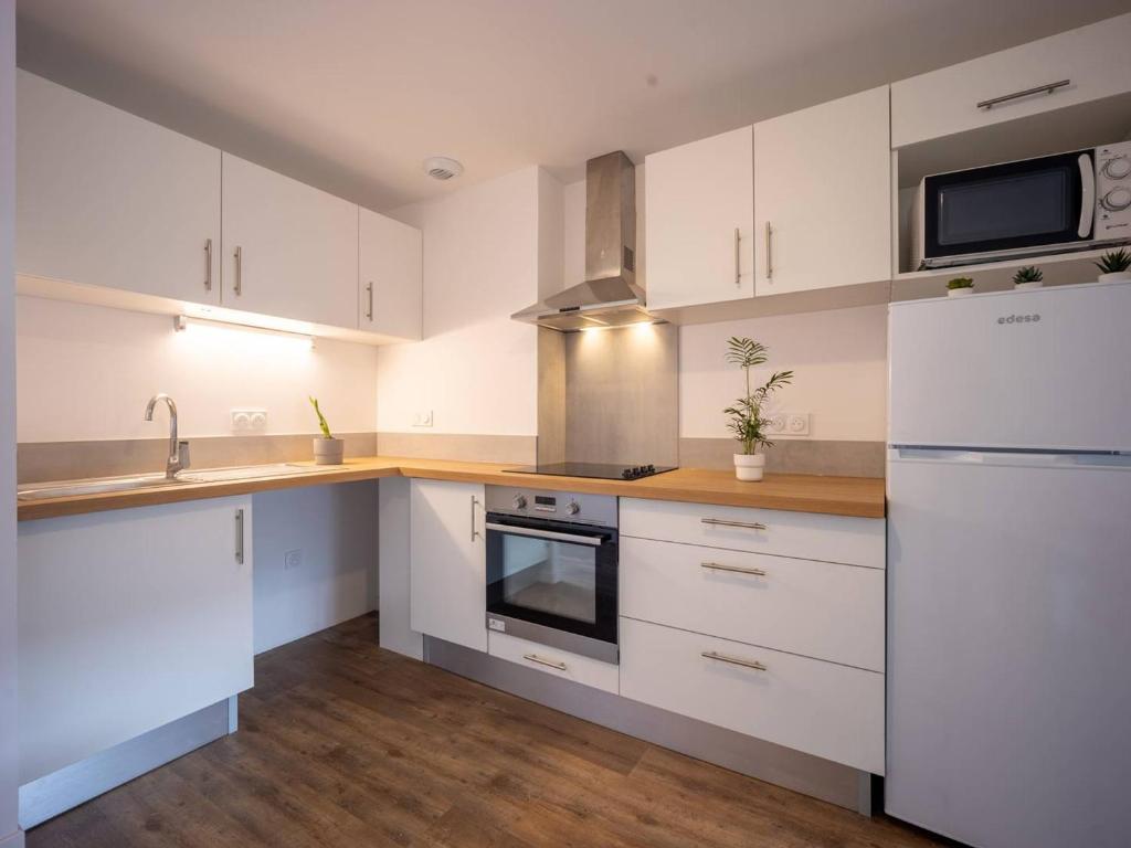 a kitchen with white cabinets and a white refrigerator at Appartement Loudenvielle, 3 pièces, 6 personnes - FR-1-695-17 in Loudenvielle