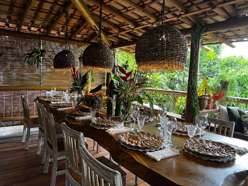 una larga mesa de madera con sillas y copas de vino en Locanda Ariramba, en Santa Cruz Cabrália