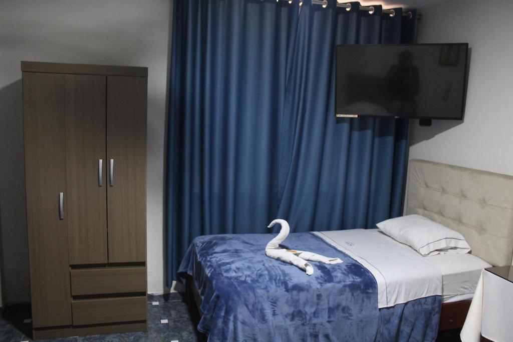 Hotel Caribe Azul في تشانساي: غرفة بجعة على سرير وتلفزيون