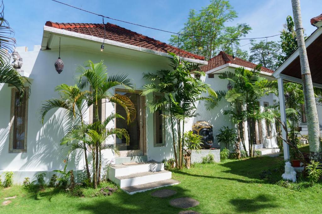 biały dom z palmami na dziedzińcu w obiekcie Surga Tropical Suites w mieście Jimbaran