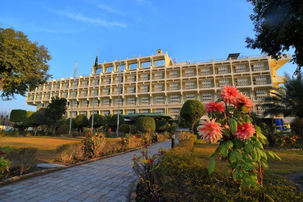 un grand bâtiment avec des fleurs devant lui dans l'établissement Peshawar Serena Hotel, à Peshawar