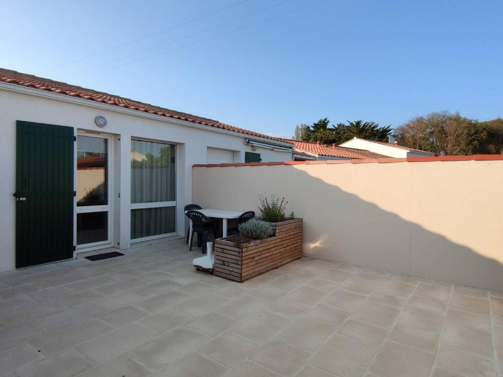 un patio avec une table et des chaises à côté d'un bâtiment dans l'établissement Appartement Calme avec Piscine, Proche Marché et Commerces - Saint-Georges d'Oléron - FR-1-246A-117, à Saint-Georges-dʼOléron